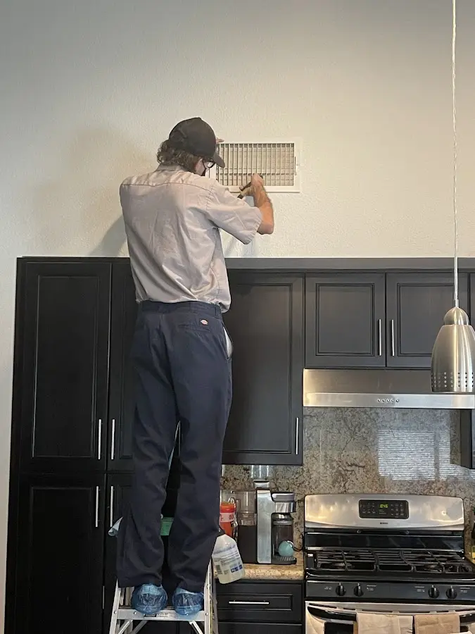 Technician inspecting an air vent during HVAC service in Eloy